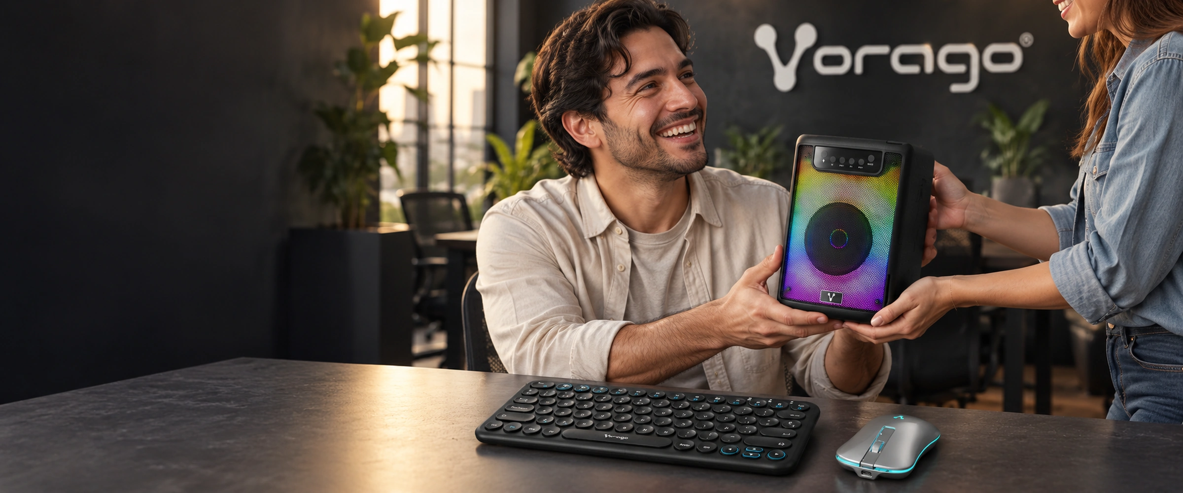 Un colaborador sonríe al recibir un bafle VORAGO KSP-205 en su escritorio, con el logo de VORAGO en la pared.